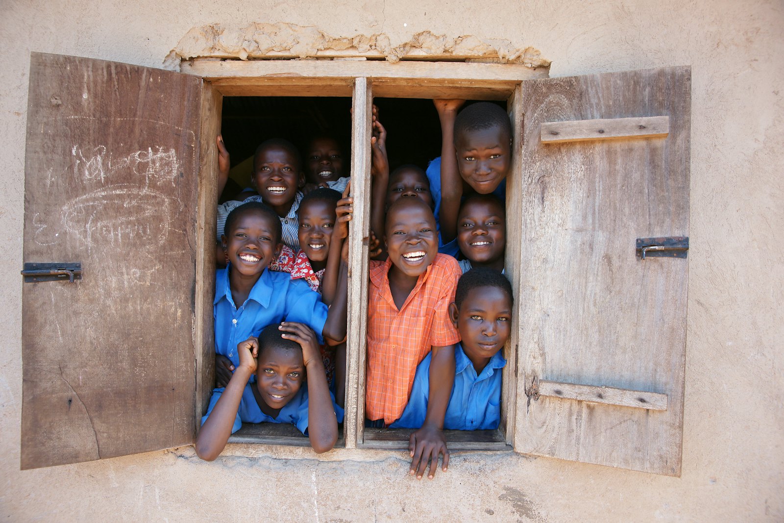 Groupe d'élèves souriants à la fenêtre de leur salle de classe